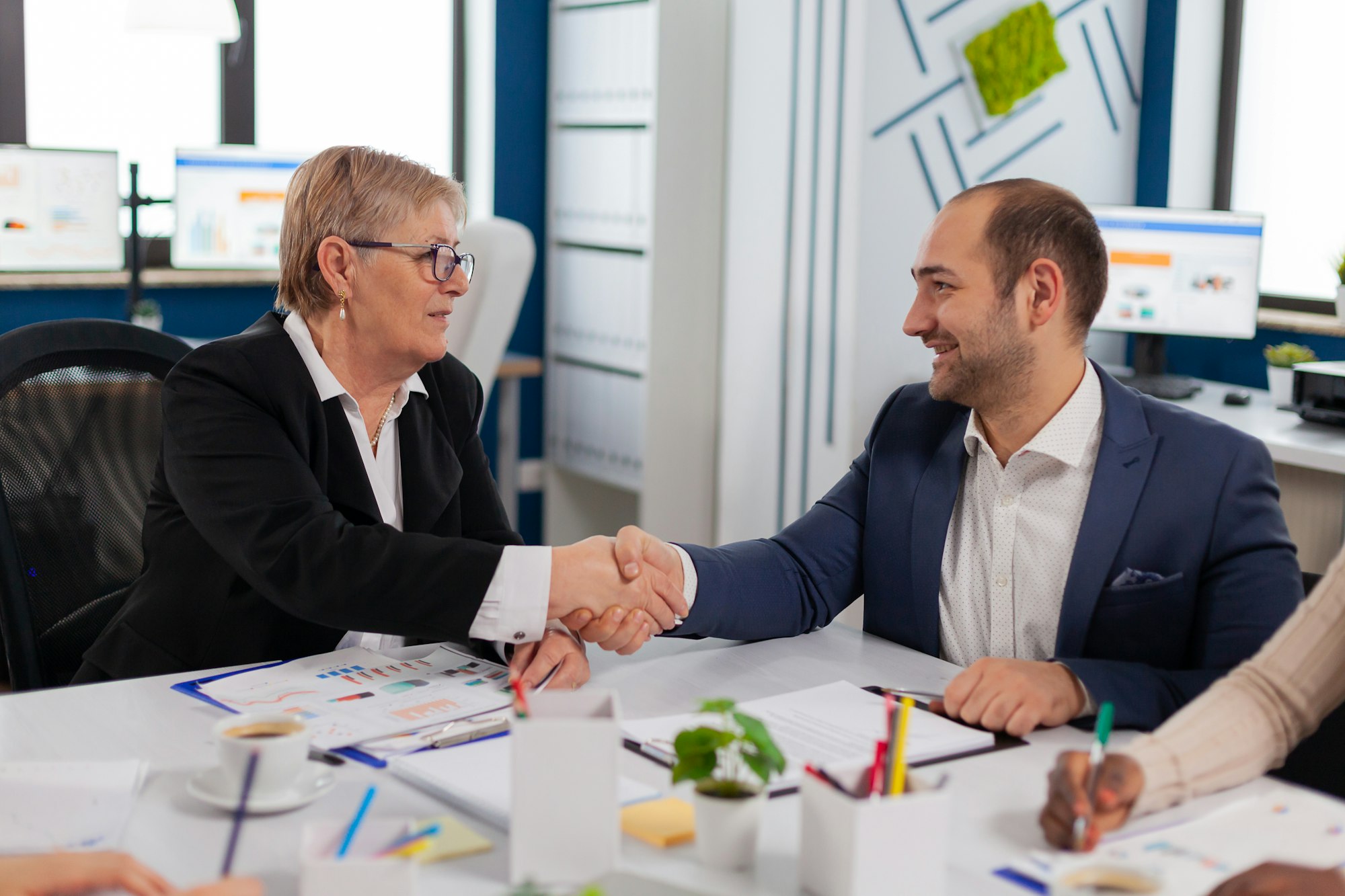 Consultant greeting international client with handshake after partnership